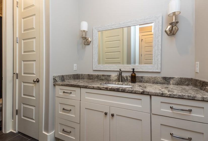 Bathroom vanity featuring a stone countertop, undermount sink, and brushed nickel faucet