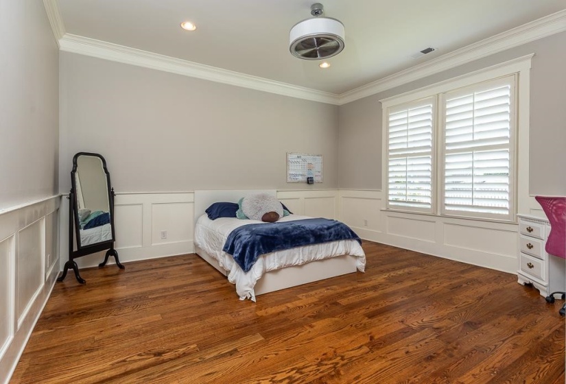 Bright room featuring rich wood-finish flooring, white wainscoting, and crown molding