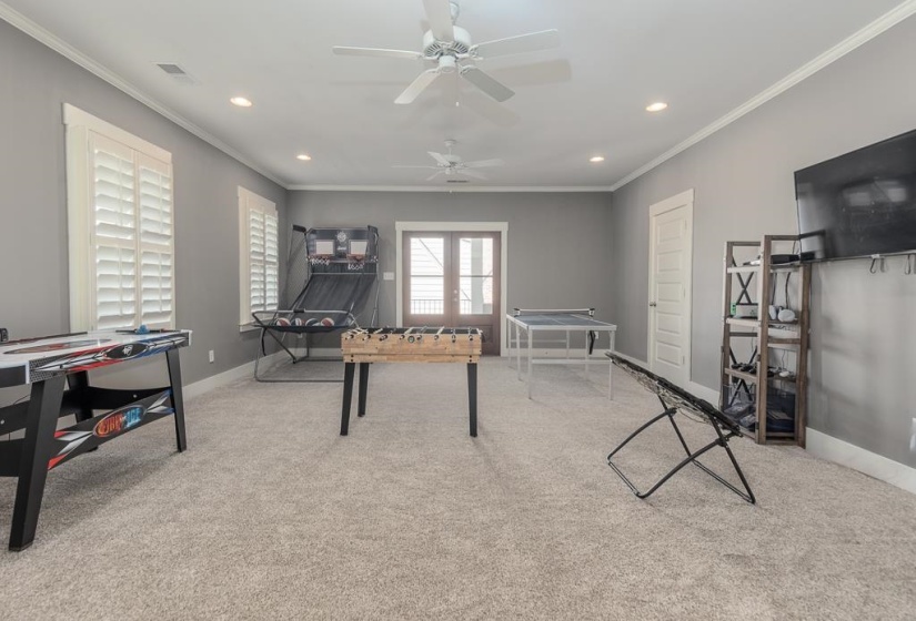 Spacious room featuring light gray wall tones, crown molding, and plush carpeting
