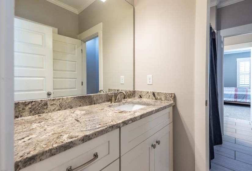Bathroom vanity featuring a light-toned stone countertop with an undermount sink and brushed nickel faucet