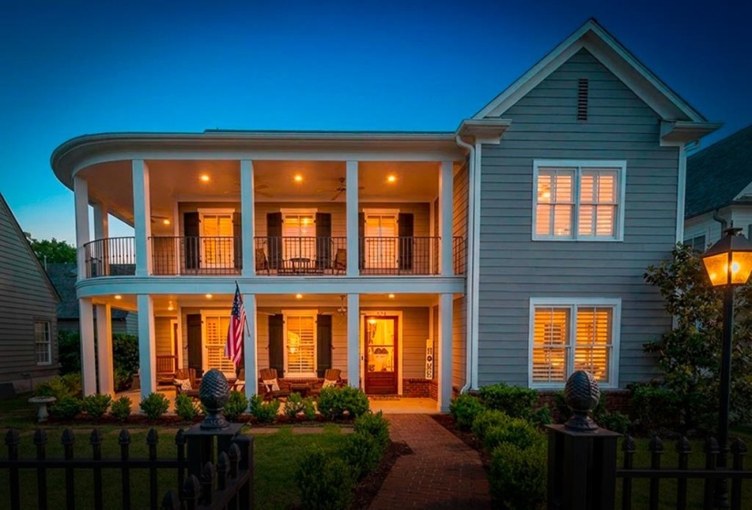 Two-story residence featuring a curved porch and balcony with black railings