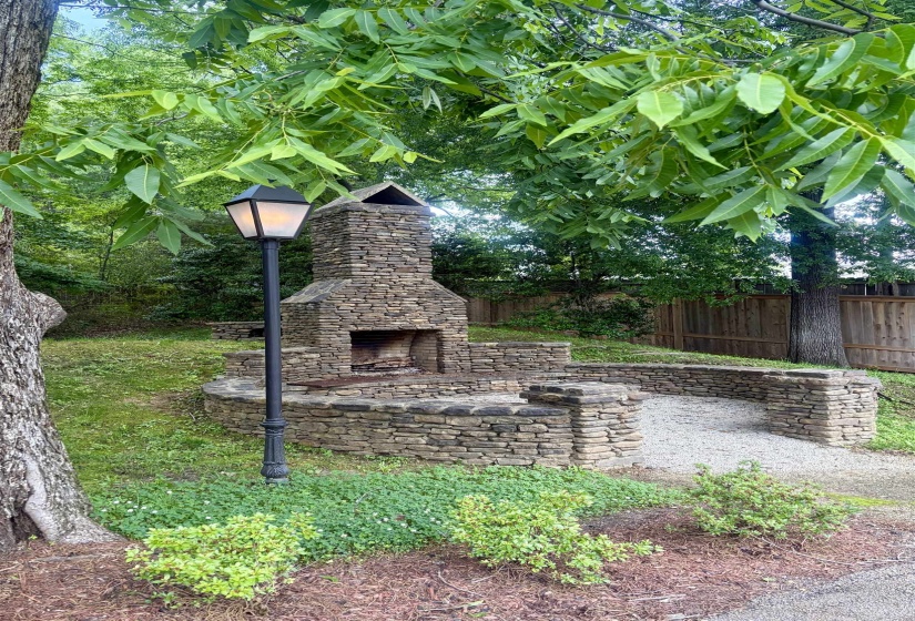 Stone outdoor fireplace featuring a hearth and integrated seating
