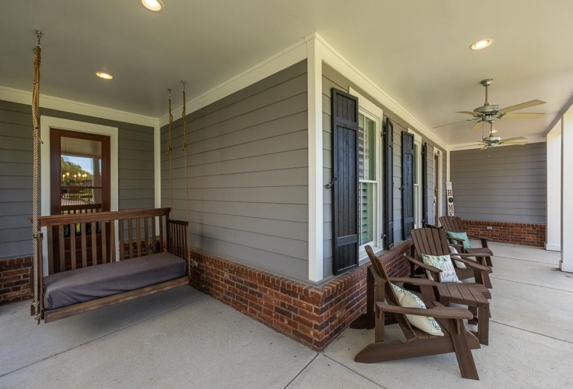 Expansive covered porch featuring a brick foundation, gray horizontal siding, white trim, and two ceiling fans