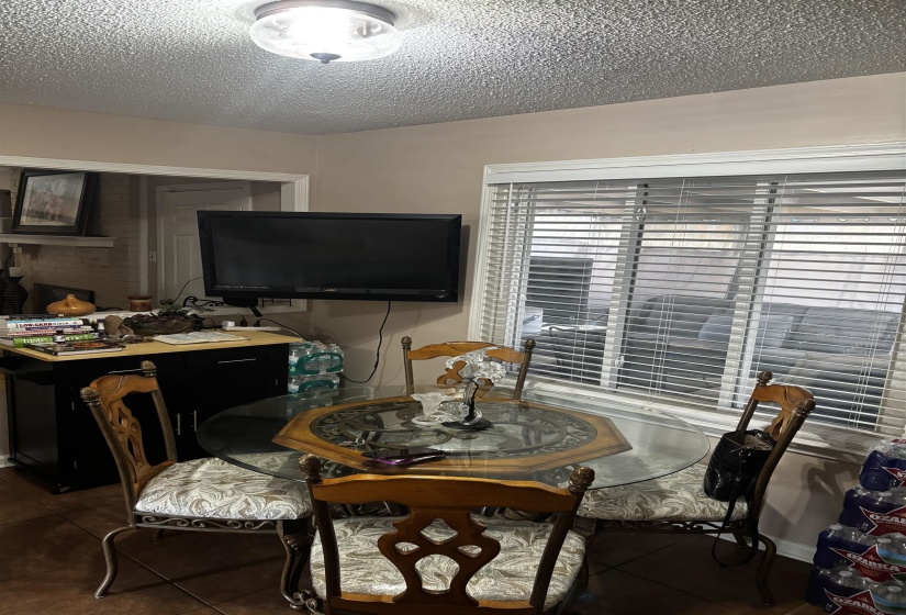 Dining area featuring a ceiling-mounted light fixture, ceramic tile flooring, and a window with horizontal blinds
