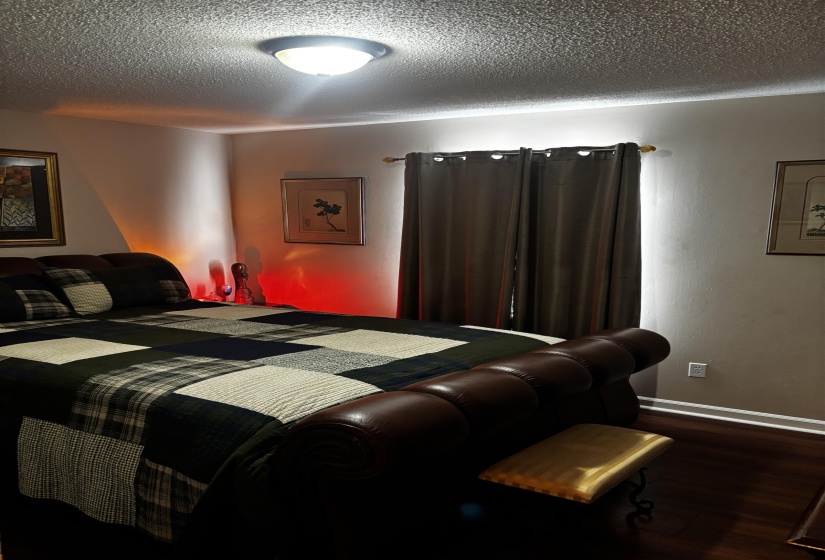 Interior room featuring wood-finish flooring, a window with draperies, and a flush-mount ceiling light fixture
