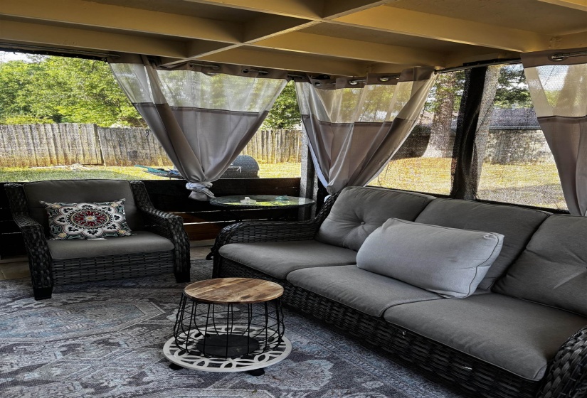 Enclosed patio featuring a lattice ceiling, sheer privacy curtains, and a patterned area rug