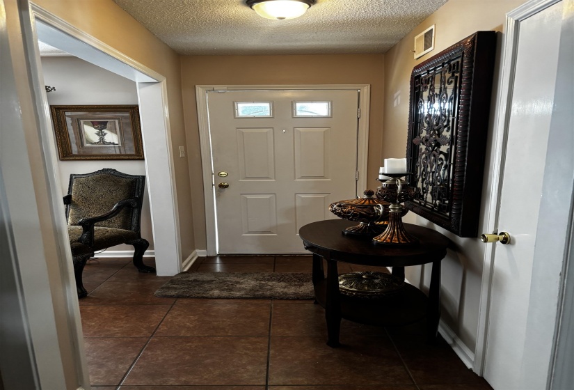 Entryway featuring a paneled door with decorative glass inserts, recessed lighting, and brown square tile flooring