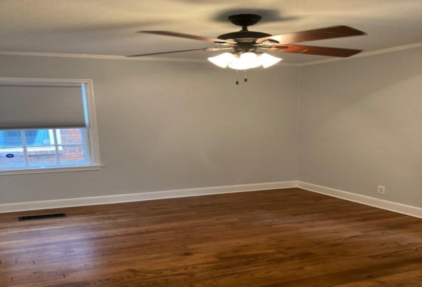 Spare room with ceiling fan, dark wood-type flooring, and crown molding