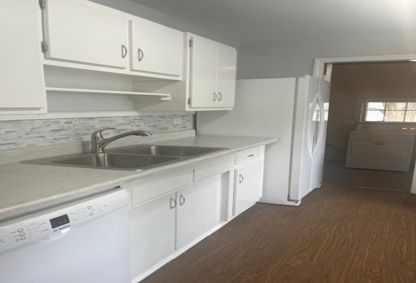 Kitchen with white cabinets, sink, dark wood-type flooring, washer / clothes dryer, and dishwasher