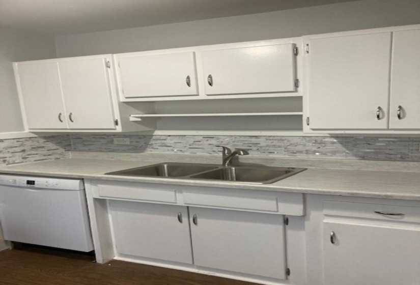 Kitchen with white dishwasher, sink, backsplash, white cabinetry, and dark hardwood / wood-style floors