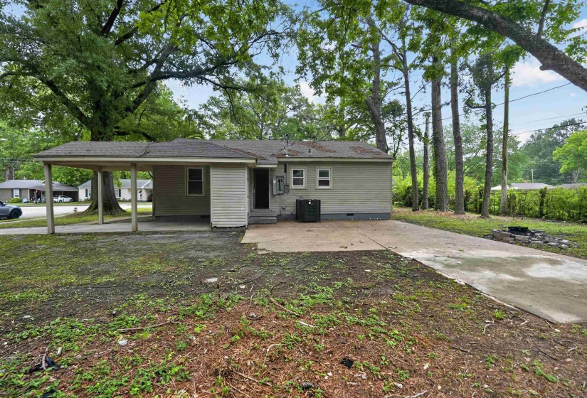 Exterior featuring light-colored siding, a covered carport, and a concrete patio