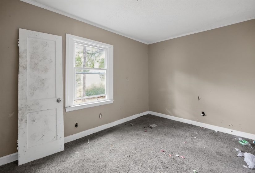 Room featuring a double-hung window with white trim, tan wall paint, and white baseboards