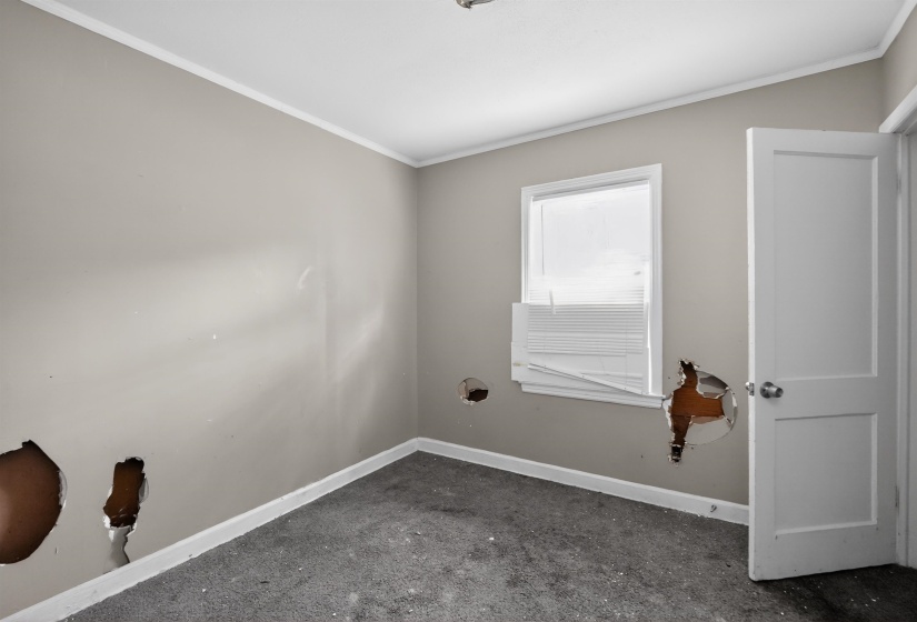 Room featuring light grey painted walls with white trim, a white window frame, and a white interior door with a silver-toned doorknob