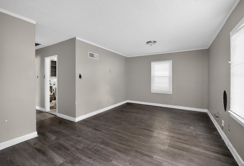 Open living area featuring wood-finish flooring, neutral gray walls, and white trim