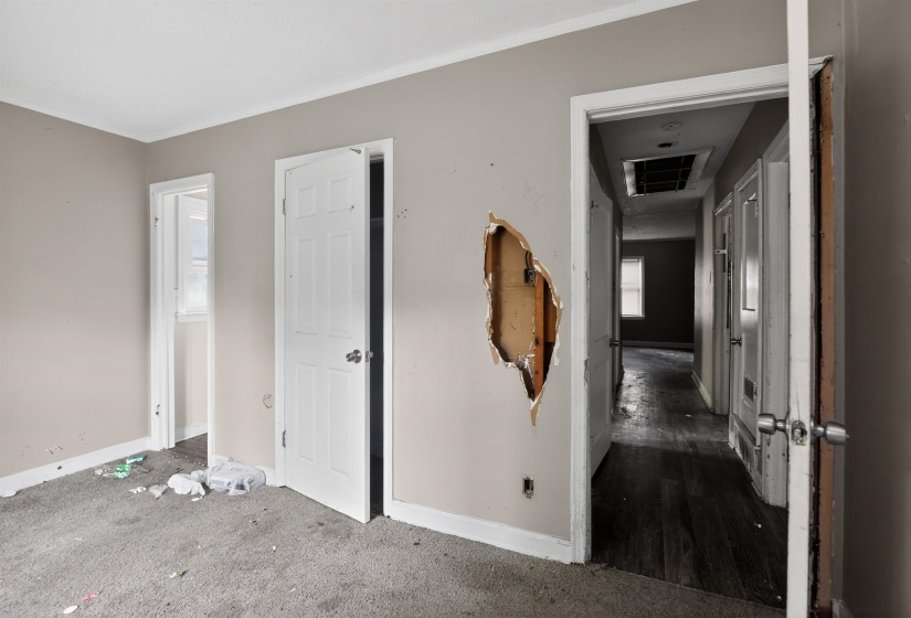 Interior space featuring light-toned walls, a white paneled door, and a hallway beyond with wood-finish flooring