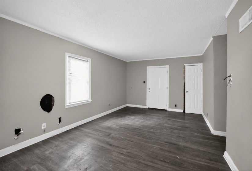 Spacious interior featuring wood-finish flooring, light grey painted walls, white baseboards, and two paneled interior doors