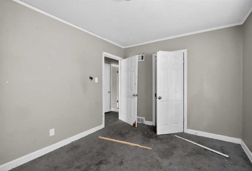 Neutral-toned interior room featuring two white six-panel doors and white baseboards