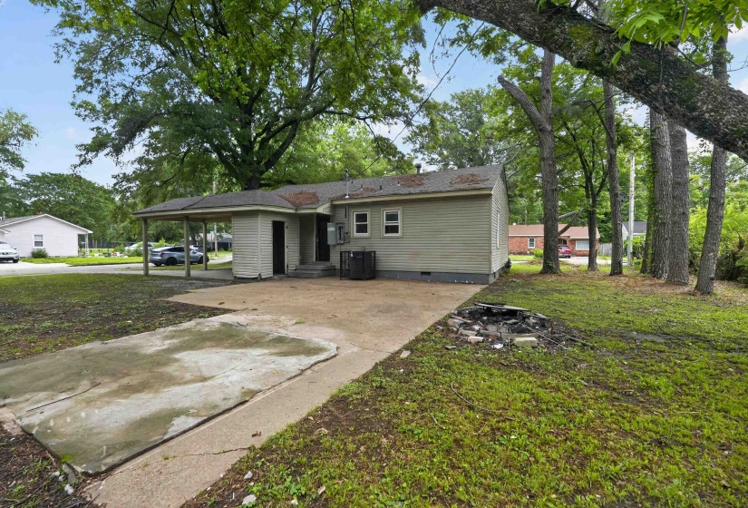 Rear exterior featuring a carport, light green siding, and a concrete driveway