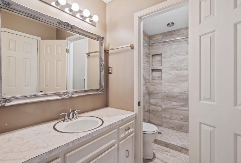 Updated primary bath with walk-in tiled shower and   modern finishes.