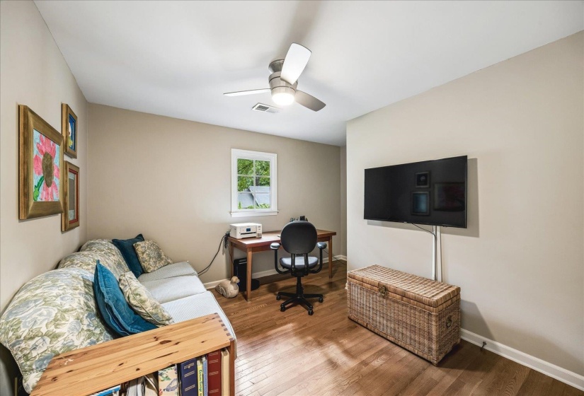 Room featuring wood-finish flooring, a white ceiling fan with integrated lighting, and neutral wall paint