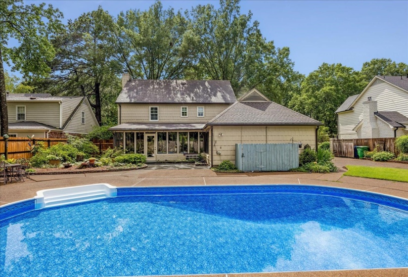 In-ground swimming pool with integrated steps, surrounded by a hardscape patio