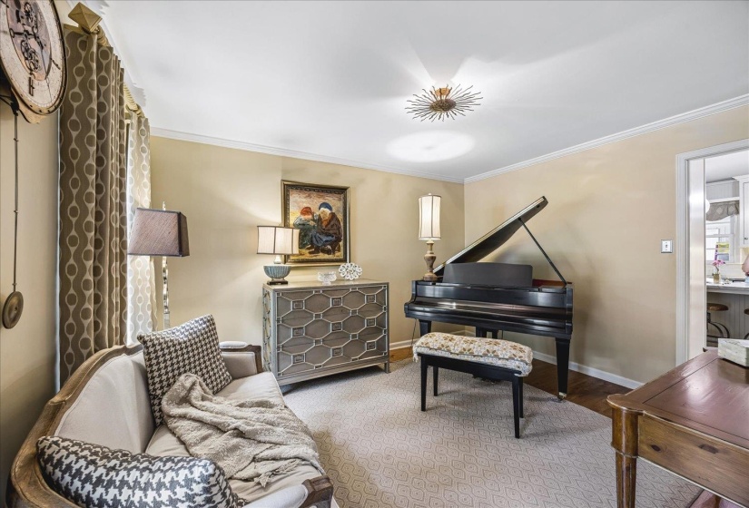 Spacious room featuring neutral wall paint, crown molding, and a patterned area rug over dark wood flooring