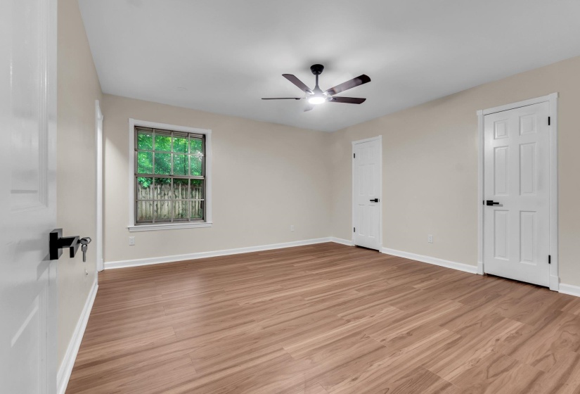 Spacious room featuring wood-finish flooring, neutral wall tones, and a modern ceiling fan with integrated lighting