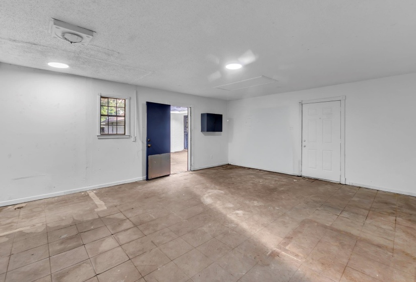 Open interior space featuring light-colored walls and a mix of tile and concrete flooring