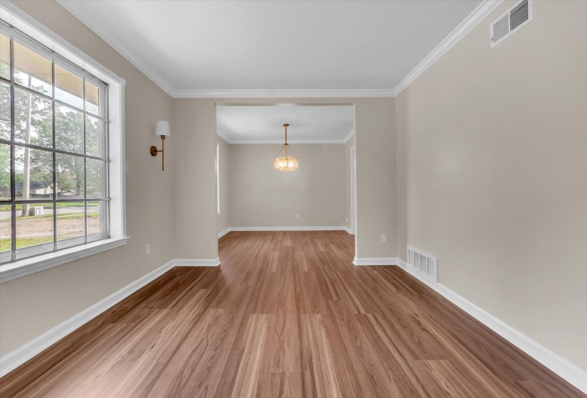 Spacious interior featuring wood-finish flooring, neutral wall tones, and white crown molding