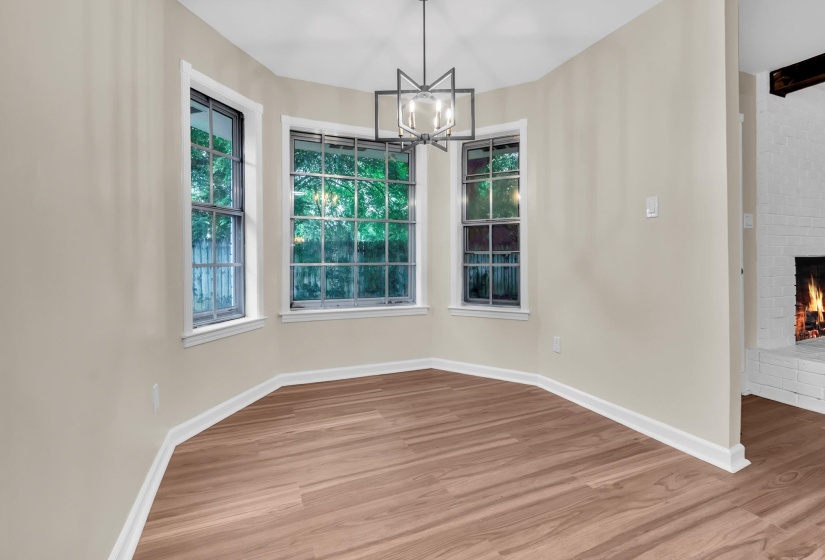 Bright breakfast nook featuring a geometric chandelier, wood-finish flooring, and a bay window configuration