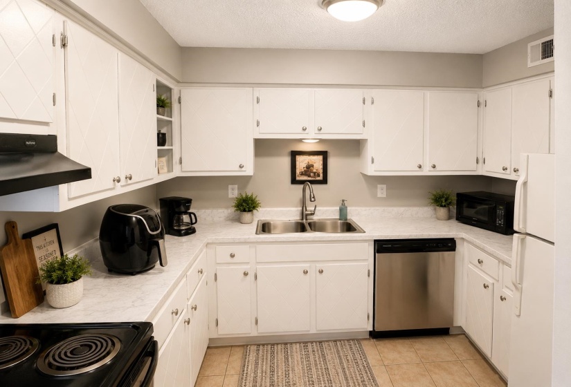 U-shaped kitchen featuring white cabinetry, light-toned countertops, and tile flooring