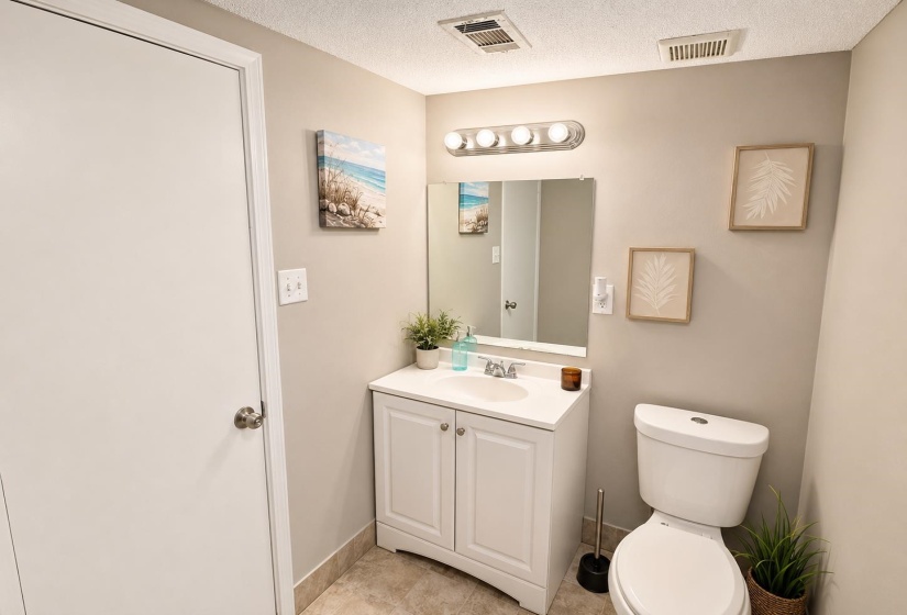 Bathroom featuring a white vanity with integrated sink, chrome faucet, wall-mounted mirror, and overhead lighting