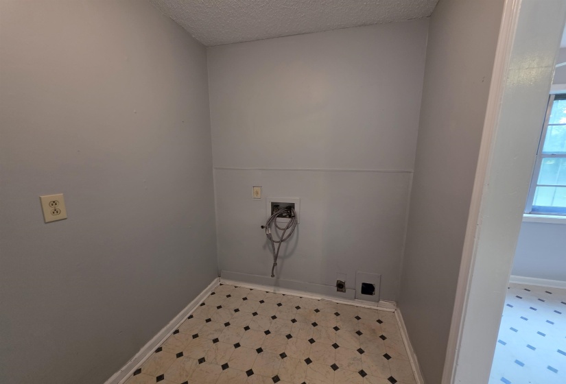 Dedicated utility area featuring a patterned vinyl floor, light gray painted walls, and textured ceiling