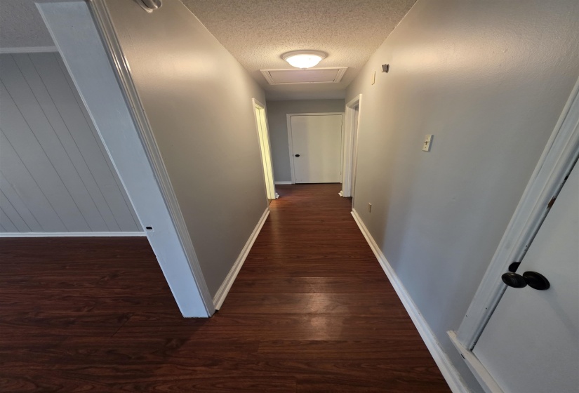 Hallway featuring wood-finish flooring, light gray wall paint, and white trim