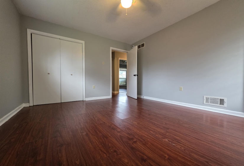 Spacious room featuring wood-finish flooring, light gray walls, and white baseboards