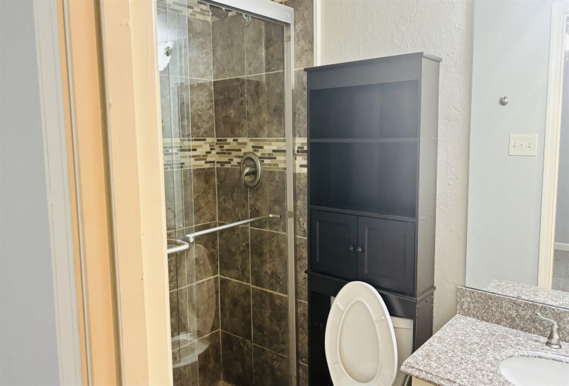 Shower with glass enclosure, brown subway tile, and decorative mosaic accent band
