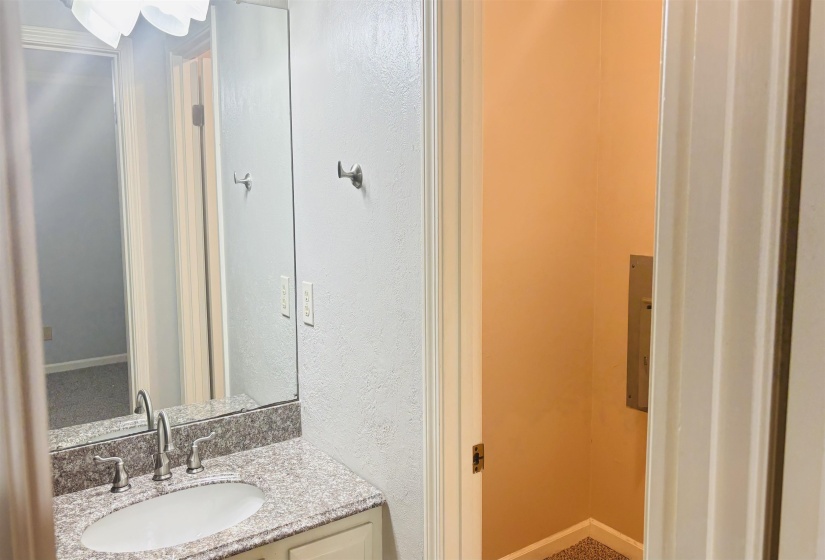 Bathroom vanity featuring a polished countertop, undermount sink, and wall-mounted mirror