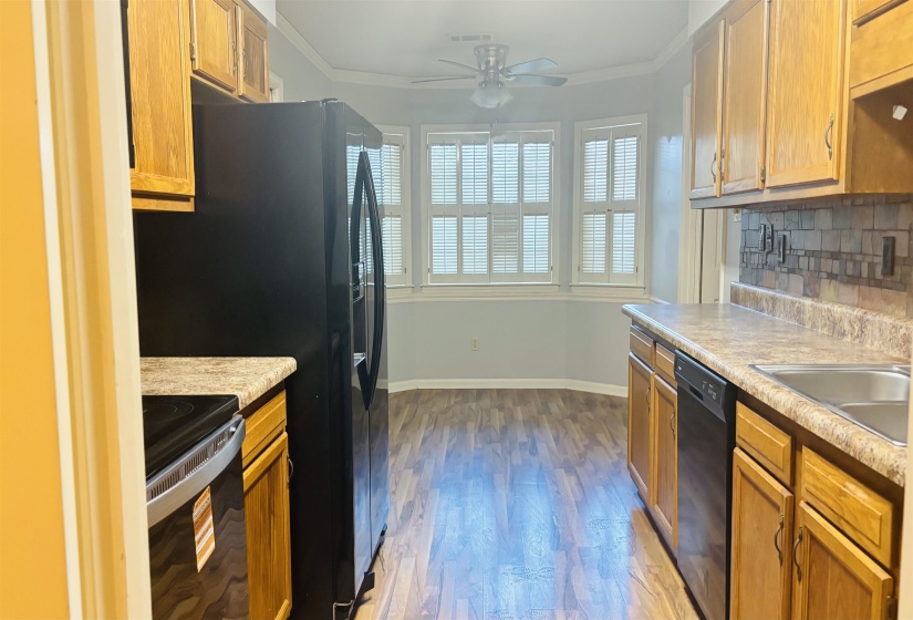 Kitchen area featuring wood-finish flooring, light wood cabinetry, and a patterned backsplash