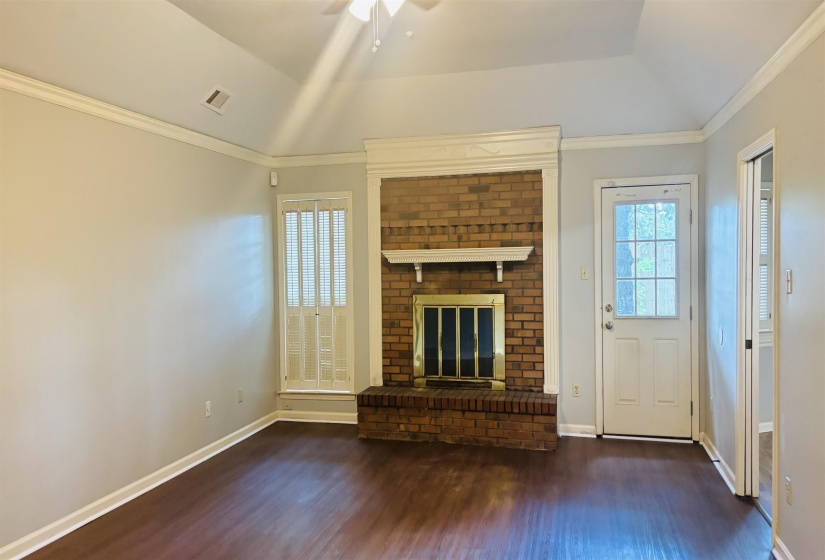 Living area featuring a brick fireplace with a decorative mantel and dark wood-finish flooring