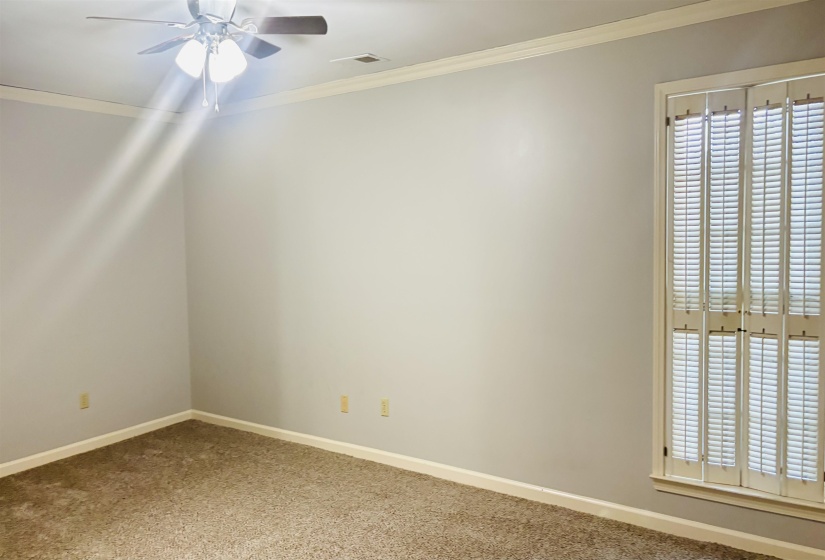 Carpeted interior space featuring neutral wall tones and crown molding