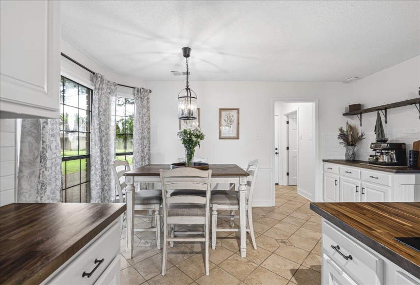 Kitchen featuring white cabinetry with dark pulls, wood-finish countertops, and a white subway tile backsplash
