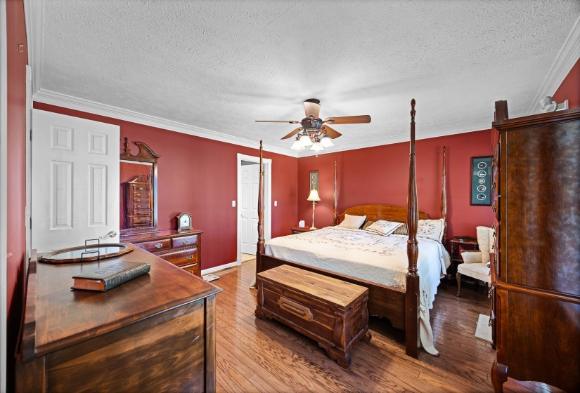 Bedroom with hardwood / wood-style flooring, a textured ceiling, ornamental molding, and ceiling fan