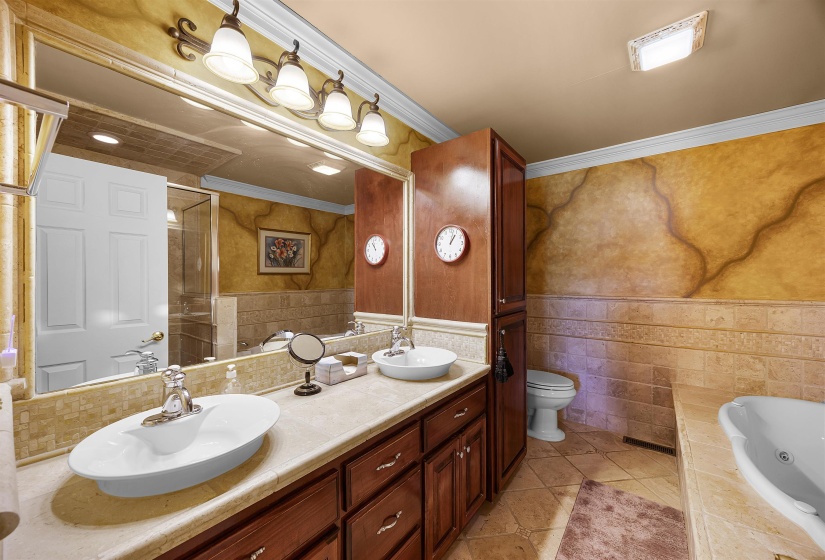 Bathroom with a whirlpool tub, light tile patterned floors, crown molding, double vanity, and tile walls