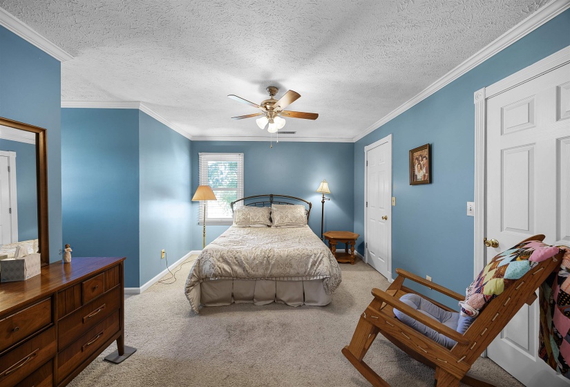 Bedroom featuring a textured ceiling, carpet, ceiling fan, and ornamental molding