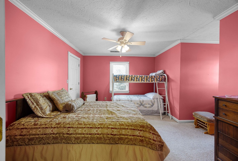 Bedroom with a textured ceiling, crown molding, light carpet, and ceiling fan
