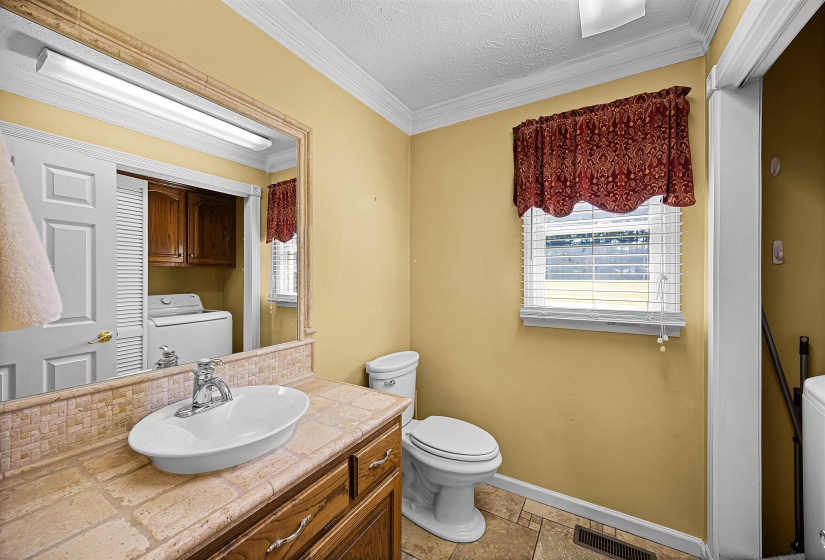 Bathroom featuring ornamental molding, vanity, a textured ceiling, washer / clothes dryer, and tasteful backsplash