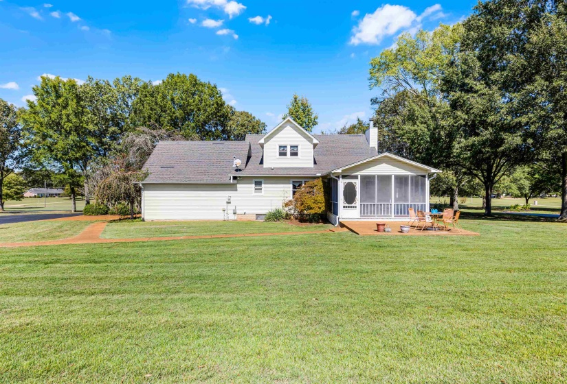 View of front of house featuring a front lawn, a sunroom, a chimney, and a shingled roof