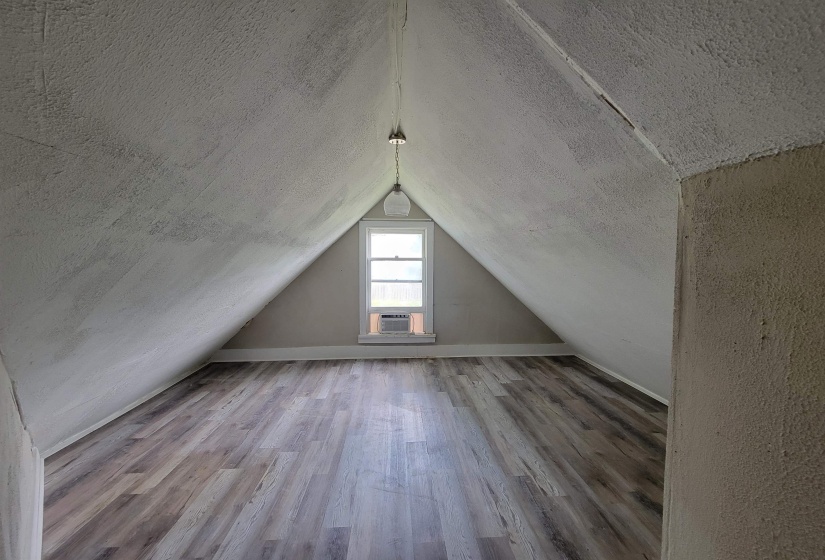 Bonus room with wood finished floors, lofted ceiling, cooling unit, and a textured ceiling
