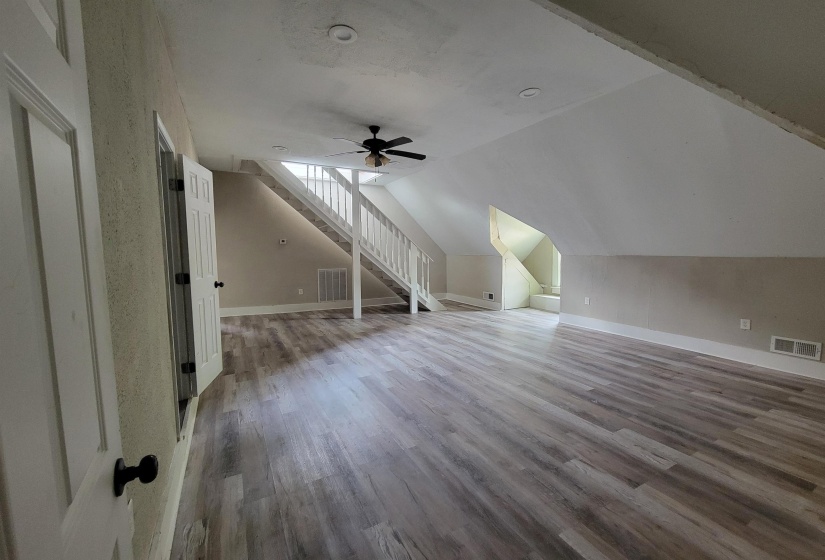 Bonus room with wood finished floors, a ceiling fan, stairs, vaulted ceiling, and baseboards