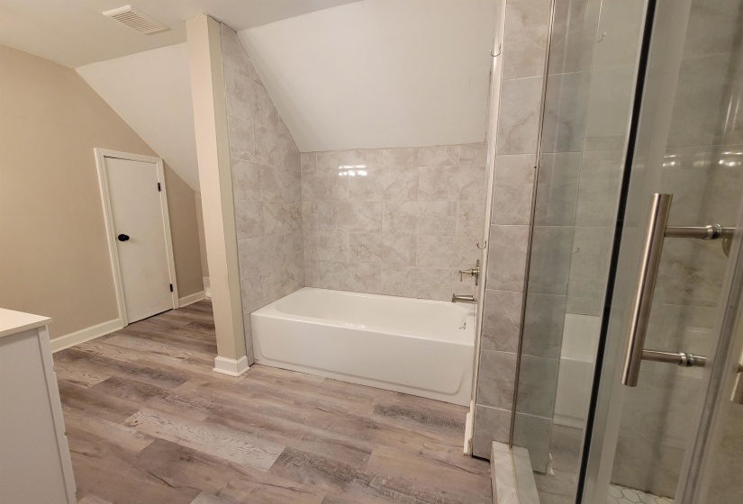 Full bathroom featuring a garden tub, lofted ceiling, a shower stall, wood finished floors, and vanity